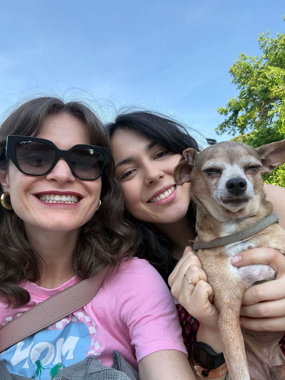 Chiara y Natalia sonriendo al sol con un chihuahua en brazos en Madrid