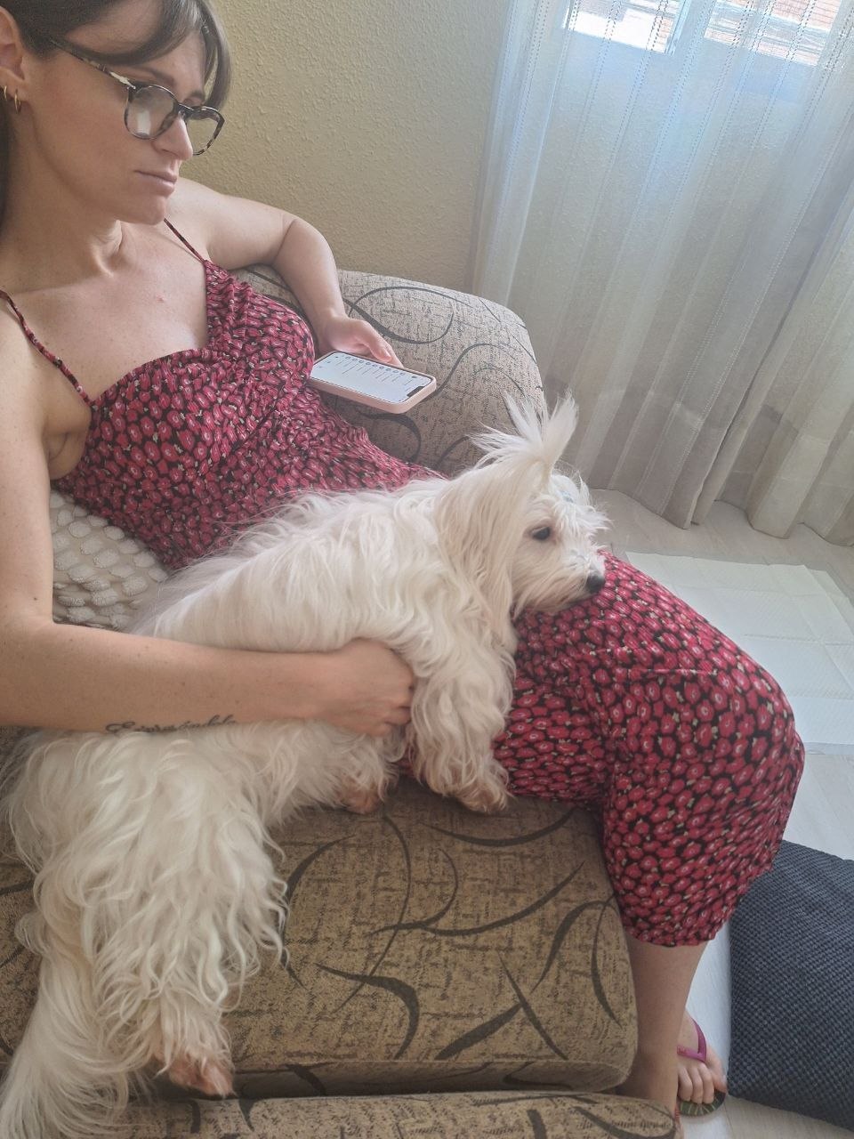 Chiara en el sillón con un perrito blanco de pelo largo acurrucado