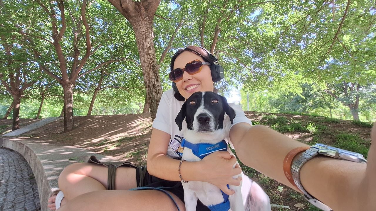 Natalia en un parque de Madrid abrazando a un perro blanco y negro